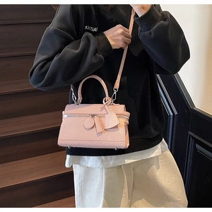 Pink textured crossbody bag shown with adjustable shoulder strap and leather details