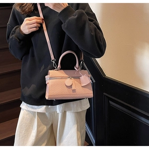 Pink textured handbag detail featuring silver hardware and a removable shoulder strap
