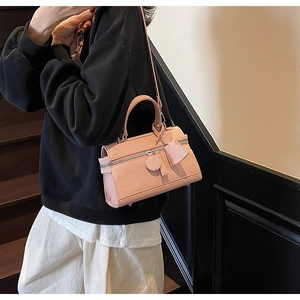 Detailed macro of pink embossed textured rectangle handbag with metal zipper and strap