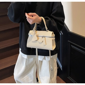 Lifestyle shot of cream woven handbag with top handle and crossbody strap detail
