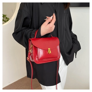 Détail du sac rouge brillant avec fermoir doré vintage et bandoulière amovible