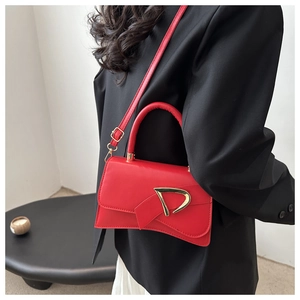 Detailed view of a red leather crossbody bag featuring a gold D-shaped buckle on a model