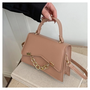 Detail of elegant dusty pink chain handbag showing geometric flap and golden hardware