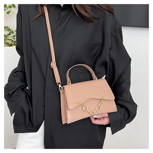 Detail of pink box bag with scalloped flap and gold chain shown on a shoulder