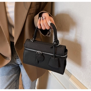 Detail of black textured handbag with top handle and crossbody strap for daily commute