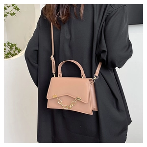 Detail of dusty pink trapezoid handbag with gold chain accent and adjustable strap