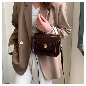 Detail of dark brown oil wax leather messenger bag with gold buckle on casual outfit