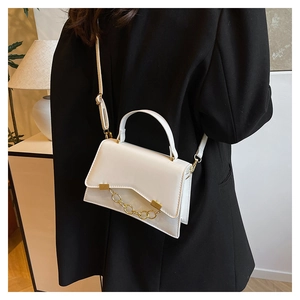 White leather box bag with gold chain strap shown on model in a modern interior setting