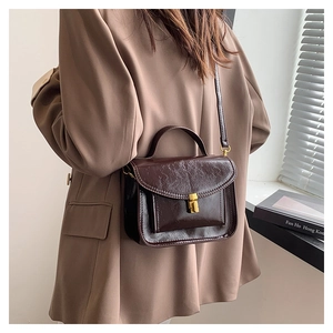 Close-up of retro dark brown oil wax leather shoulder bag with golden metal twist lock