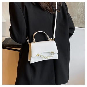 Close-up of a white leather box bag with gold chain strap worn by a model in a black suit