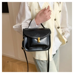 Detail of a vintage black patent leather handbag featuring a gold turn-lock closure
