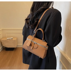 Textured brown boston bag styled on a black blazer with adjustable crossbody strap