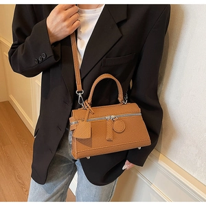Close-up of brown textured leather handbag with silver hardware and woven pattern detail