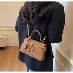 Close-up of brown woven texture handbag with silver dual zippers and detachable strap