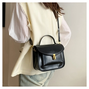 Détail du sac messager noir vintage avec fermoir pivotant doré et poignée supérieure