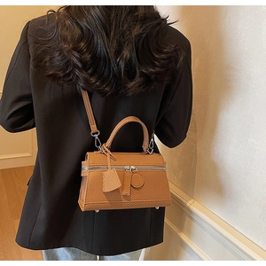 Detail of brown grain leather box handbag with metal feet and detachable strap
