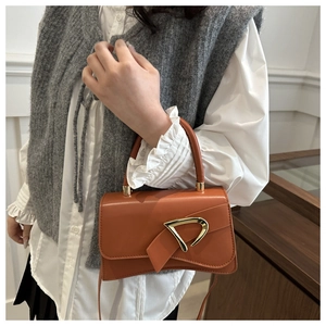 Close-up of amber leather mini bag with unique gold clasp worn by a model
