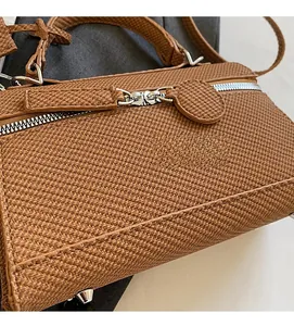 Macro shot of brown woven texture bag with silver dual zippers and metal rivets