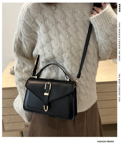 Detail shot of the elegant black crossbody bag featuring a distinctive gold U-shaped buckle
