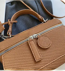 Close-up of smooth silver zippers and woven texture on a brown crossbody bag