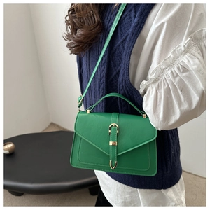 Detail view of a green faux leather handbag with a gold buckle and adjustable strap