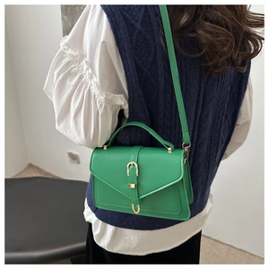 Detail view of a bright green crossbody bag with gold metal buckle and leather strap