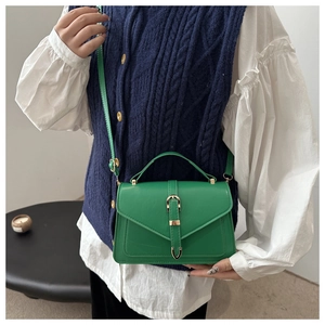 Elegant green leather crossbody bag with gold metal buckle shown in a lifestyle fashion pose
