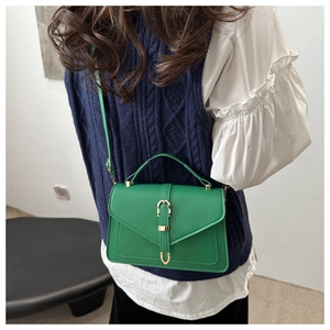 Styling shot of a bright green mini square crossbody bag with gold buckle hardware