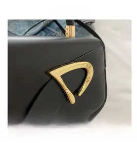 Close-up of golden D-shaped metal clasp on premium black leather crossbody flap bag