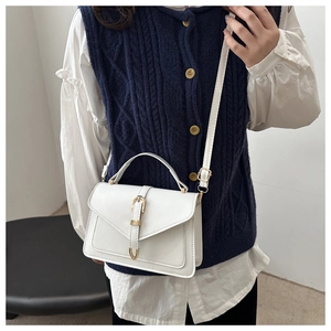 Detailed shot of white square crossbody bag with gold hardware and top handle on a model