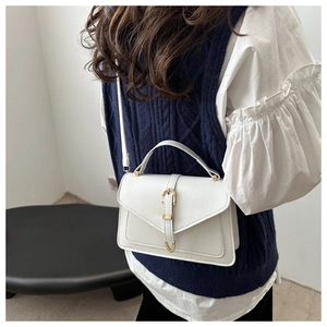 Detail view of cream vintage crossbody bag with gold horsebit buckle on model