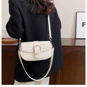 Detail of cream white saddle bag with silver horseshoe buckle and vegan leather texture