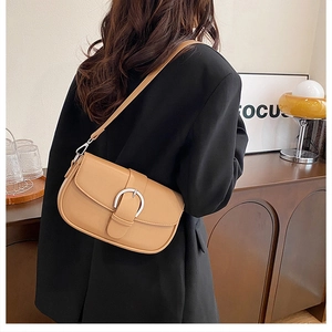 Detail of camel brown saddle bag with U-shaped buckle worn by a model in vintage room