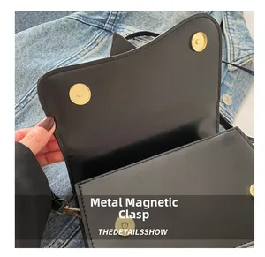 Detail of golden magnetic snap closure on black leather handbag with curved flap edge