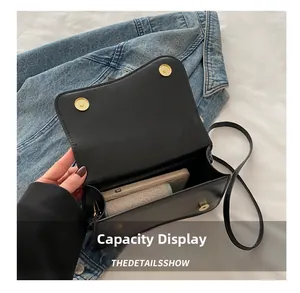 Interior capacity of black flap crossbody bag showing space for smartphone and small pouch