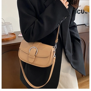Detail of light brown PU leather saddle bag with silver horseshoe buckle and strap