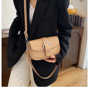Detail of light brown retro saddle bag with silver round buckle worn with a black blazer