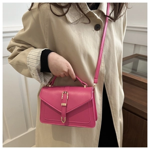 Model showing a rose pink leather crossbody bag with gold metal buckle and strap