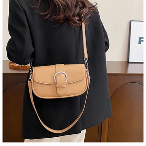 Detail view of camel saddle bag with silver buckle and adjustable shoulder strap
