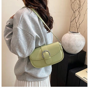Detail of light green leather saddle bag with silver buckle worn as an underarm bag