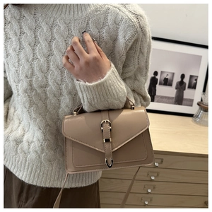 Detail of beige leather crossbody bag with a gold buckle strap and sleek flap design