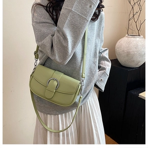 Side view of a light green leather saddle bag with silver buckle worn by a model