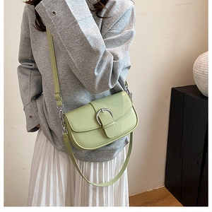 Detail of mint green saddle bag featuring a silver horseshoe buckle and fine stitching
