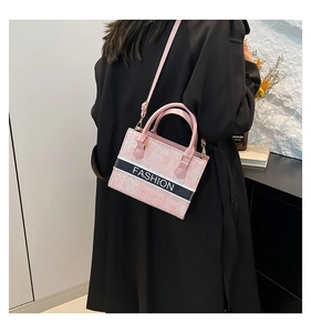 Detailed look at the pink tote bag featuring a black FASHION logo strap and gold hardware