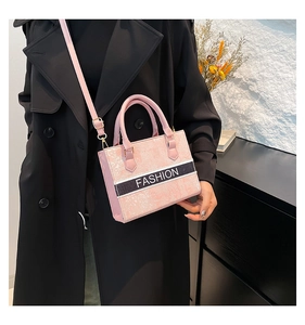 Detail of elegant pink textured handbag with Fashion text and golden metal hardware