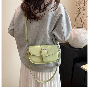 Detail of light green vintage saddle bag featuring a large silver horseshoe metal buckle