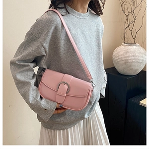 Detail shot of a light pink saddle bag with silver round buckle worn by a model
