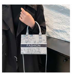 Detail of high-capacity tote bag featuring gray jacquard pattern and FASHION text strip