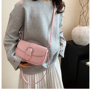 Close-up of pink leather saddle bag featuring a stylish silver horseshoe buckle detail