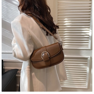 Detail of a brown leather saddle bag featuring a stylish silver horseshoe metal buckle